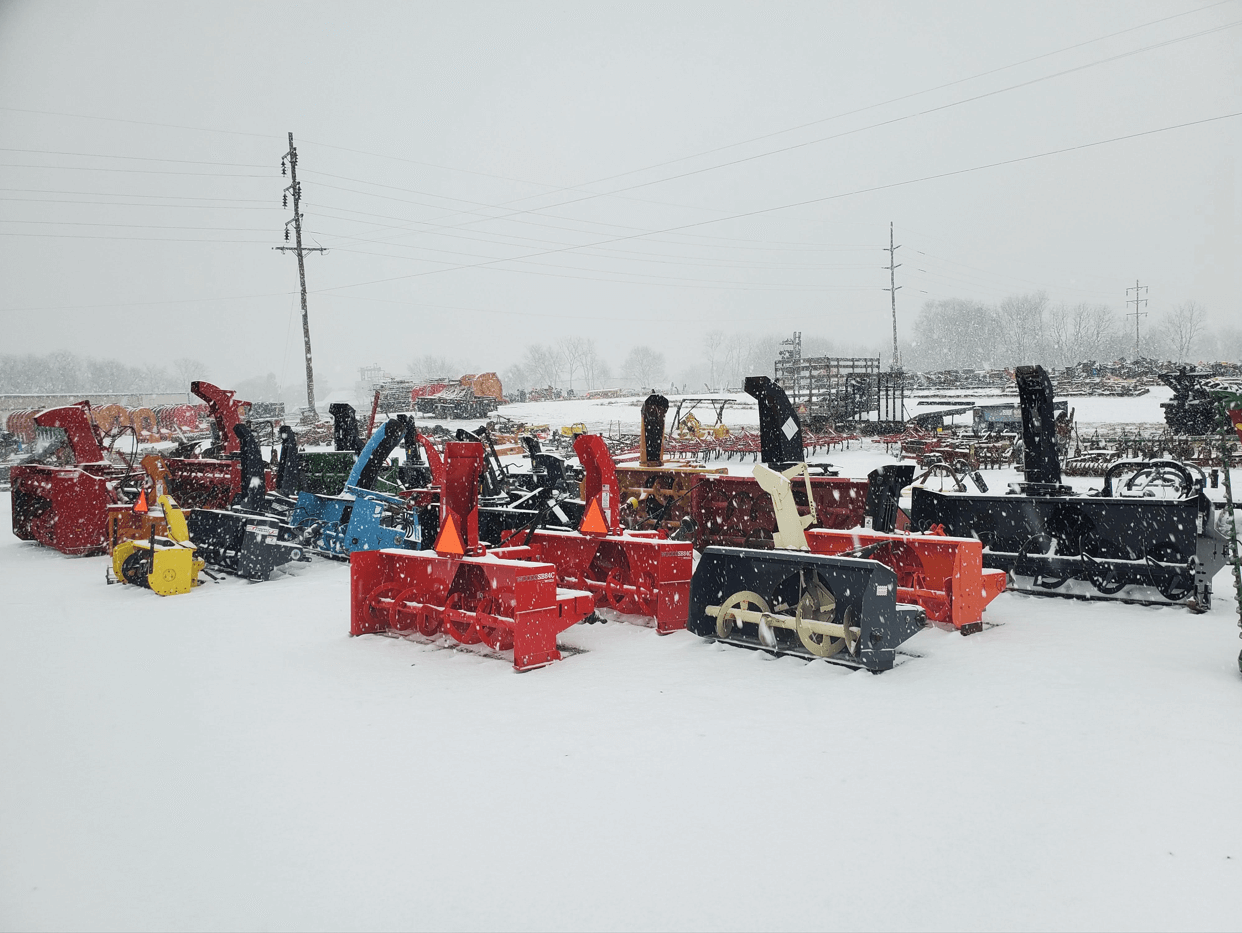 Snow blowers and blades lined up in winter conditions